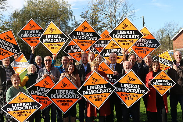 A large group of Liberal Democrats holding signs that say Liberal Democrats Winning Here