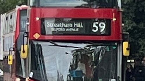 A red double decker bus picking up passengers