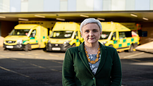 Alex Brewer MP standing in front of ambulances