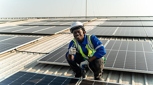 A man putting solar panels on a roof.
