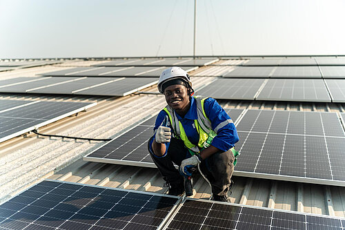 A man putting solar panels on a roof.