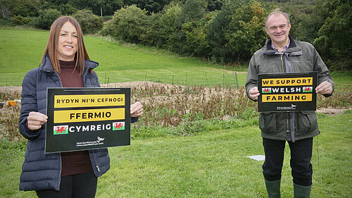 [Translate to Welsh:] Welsh Lib Dem Leader Jane Dodds and UK Leader Ed Davey holding signs saying "Back Welsh Farming"