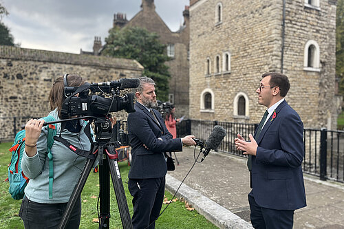 Tom Gordon stood being interviewed on College Green outside the Houses of Parliament