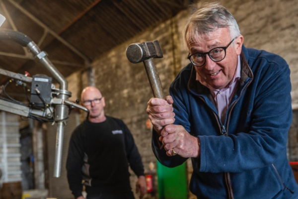 Jamie Stone pictured whacking a barrel of Whisky with a hammer