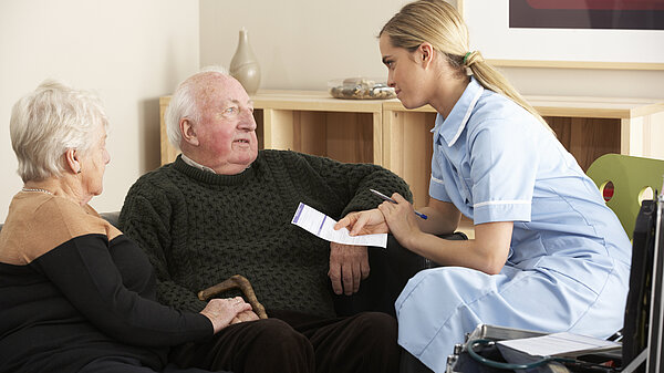 A nurse treating two old people.