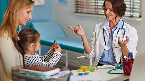 A mother holding a child whilst a GP speaks to them