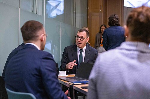 Tom Gordon seated speaking to MPs around a table
