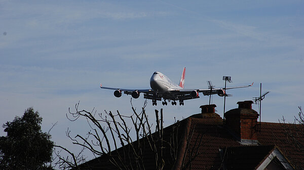 A plane flying close to houses.