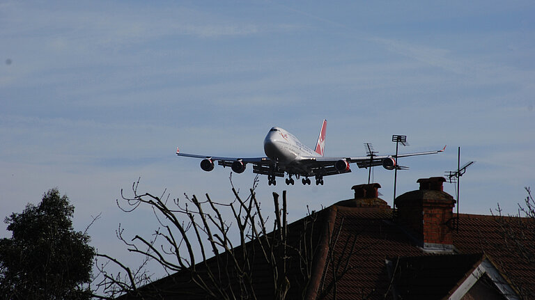 A plane flying close to houses.
