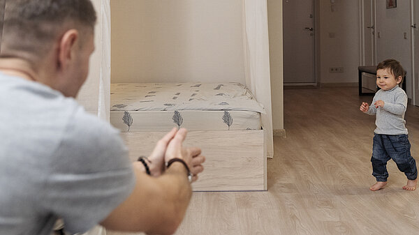 A child running towards a parent in an empty bedroom