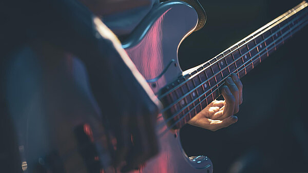 A base guitar, the hands playing the guitar are visible.