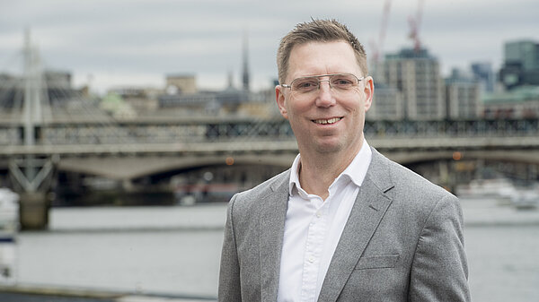 A headshot of Rob Blackie pictured in a white shirt with a navy blazer