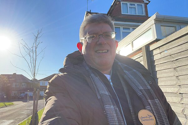 Simon is pictured smiling and wearing a Liberal Democrat badge.