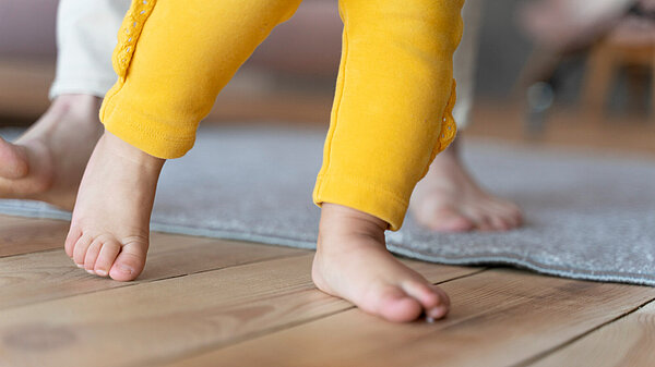 Photo baby learning how to walk and being helped by his mother