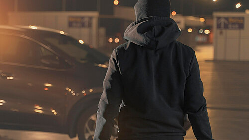 A hooded man holding a knife.