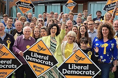 Oxfordshire Liberal Democrats cheering and holding signs that say "Liberal Democrats"