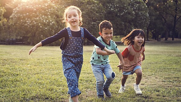 Three children running in a garden