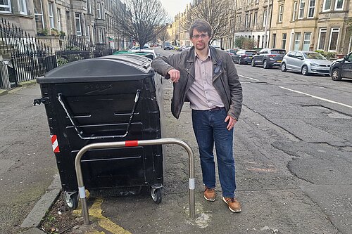 Jack standing next to a set of communal bins