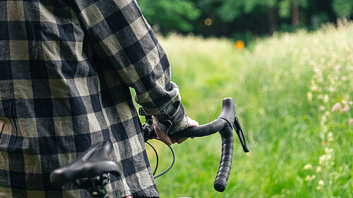 A cyclist walking their bike through a meadow