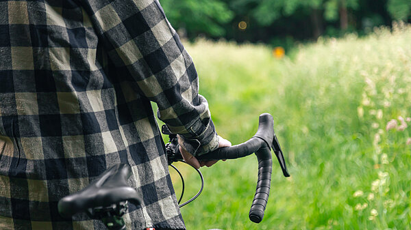 Someone pushing a bike through a meadow