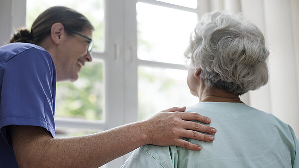 A carer helps an eldery lady to stand