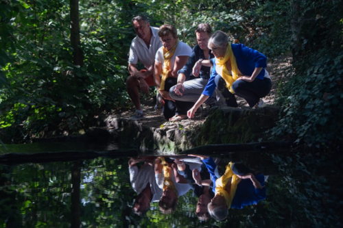 A group of people - including Liberal Democrat councillors and the MP for St Albans, Daisy Cooper - are crouching at the bank of the River Ver, looking at the state of the river.