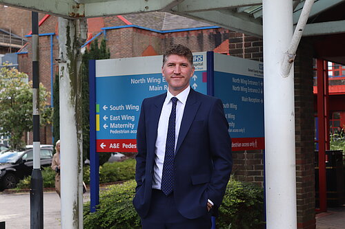 Edward Morello MP in a navy suit stood outside Dorset County Hospital