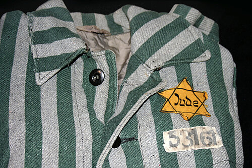 Striped outer uniform with yellow Star of David that Jews were forced to wear at Auschwitz. Photo © Takkk CC by-SA 3.0 via Wikipedia Commons.( File:Auschwitz outerwear distinguish yellow Star of David.jpg - Wikimedia Commons)