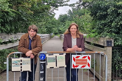 Jack and Sanne behind a fence with a sign saying "Bridge Closed"