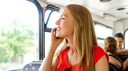 Teenager on a bus, talking on her phone.
