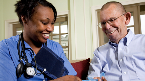 Nurse offering medication to old man.