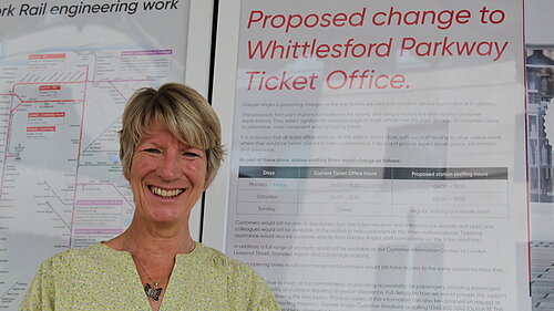 Pippa Heylings, Liberal Democrats parliamentary candidate for South Cambridgeshire, stands in front of an announcement about changes to the Whittlesford Parkway ticket office