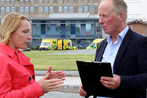 Helen discusses corridor care with a colleague outside a local hospital