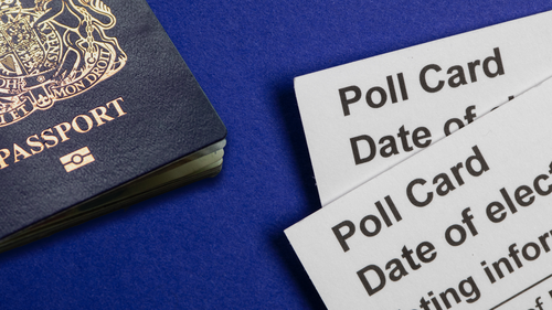 Polling cards and a blue UK passport on a blue background