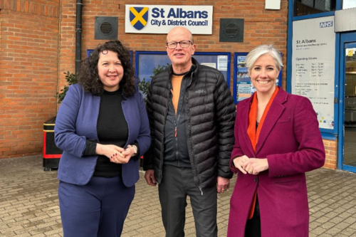 Victoria Collins MP, Councillor Paul de Kort, and Daisy Cooper MP (from left to right) are standing in front of the St Albans District Council building.
