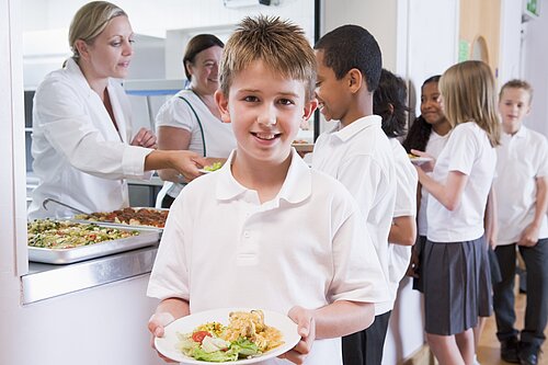 A boy holding a plate of food after leaving the dinner line.