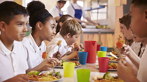 Four children eating food from a plate.