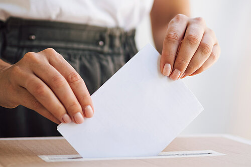A person putting a ballot paper into a ballot box