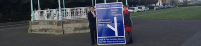 Lynne Beaumont and Antony Hook in Folkestone with road sign to prosperity or Euro exit and Unemployment