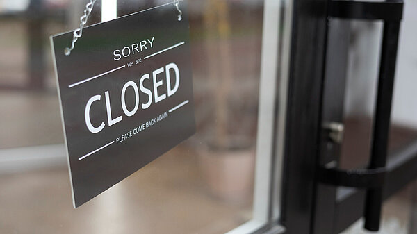 A sign hanging in a shop door window reading "Sorry we are closed"