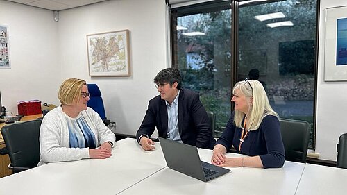 Zoe Franklin, Paul Follows and Julia McShane seated at a table, in discussion.