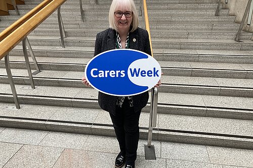 Beatrice Wishart holding a Carers Week sign.