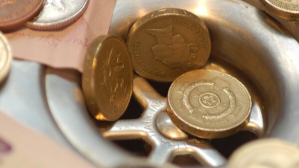 Pound coins going into a drain.