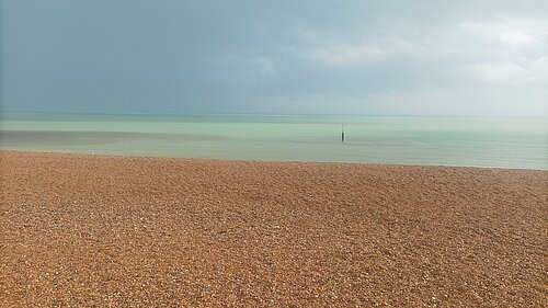 Stony beach with threatening cloud over sea.