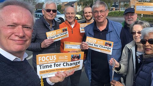 Lib Dems holding up Lib Dem leaflets while taking a photo