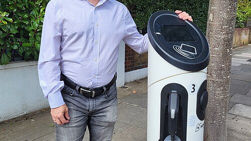 Cllr Gary Malcolm stood next to an EV charging station.