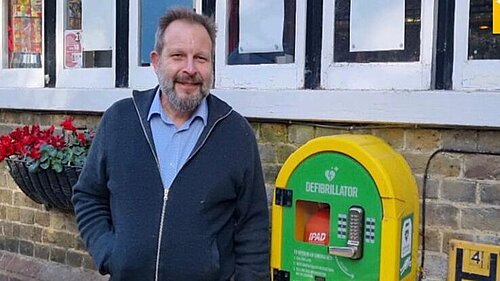 Andrew Millsom next to a defibrillator