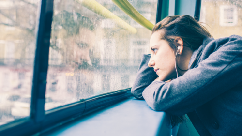 A woman looks out of a window on the top deck of a London Bus.