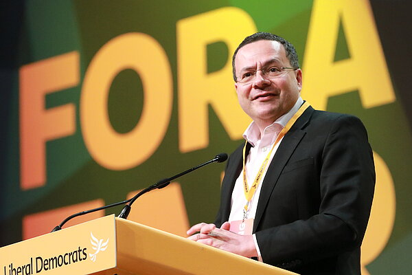 Mark Pack. Mark is photographed stood at the podium at Liberal Democrat conference.