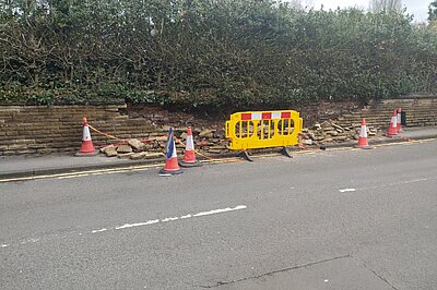 The collapsed wall which is blocking the whole pavement